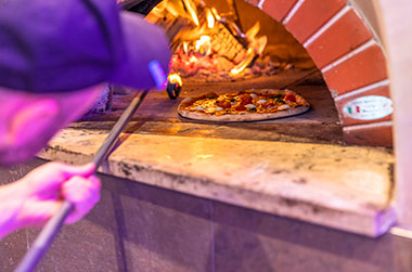 Schauen Sie selbst, wie Ihre Pizza im Holzofen gebacken und dann frisch zubereitet wird